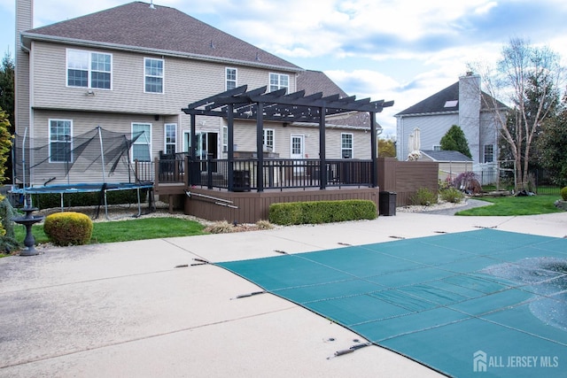 23 Keswick Cir, Monroe, NJ 08831 - back of property featuring a pergola, a trampoline, a wooden deck, and a patio area