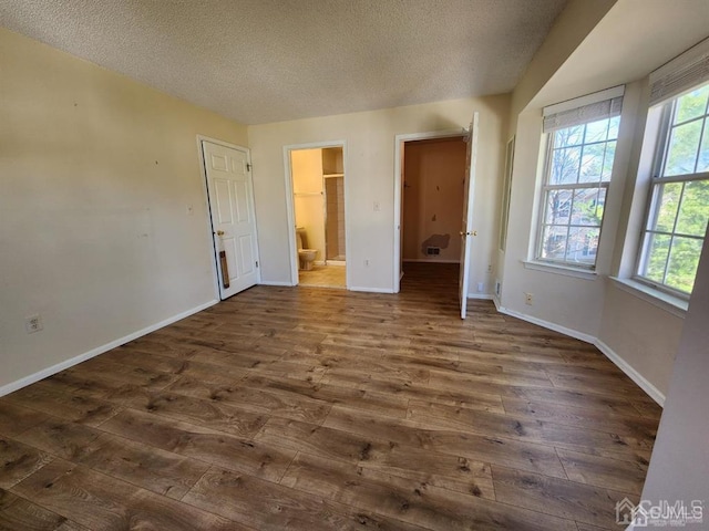 unfurnished bedroom featuring multiple windows, baseboards, and dark wood-type flooring