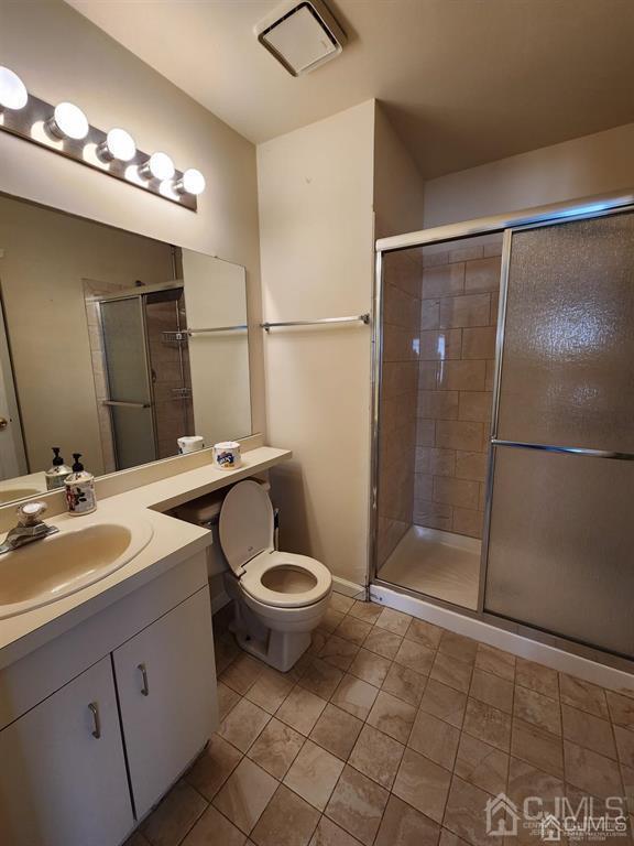 bathroom featuring toilet, a stall shower, visible vents, and vanity