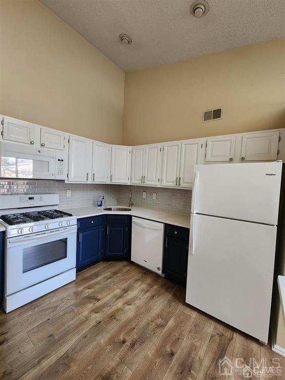 kitchen featuring visible vents, light countertops, white appliances, and white cabinetry