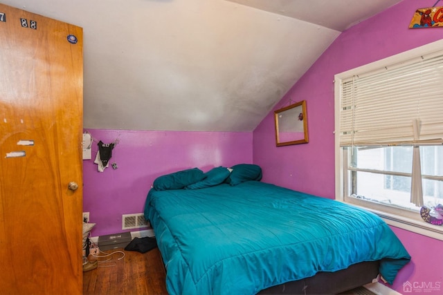 bedroom with lofted ceiling, visible vents, and wood finished floors