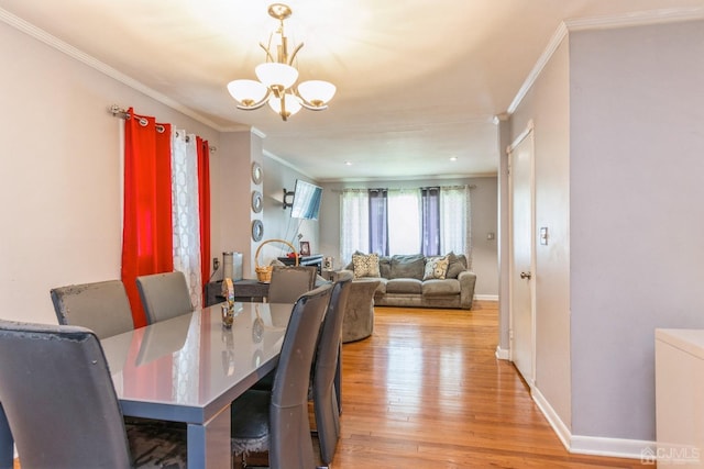 dining room featuring crown molding, an inviting chandelier, and light wood-type flooring