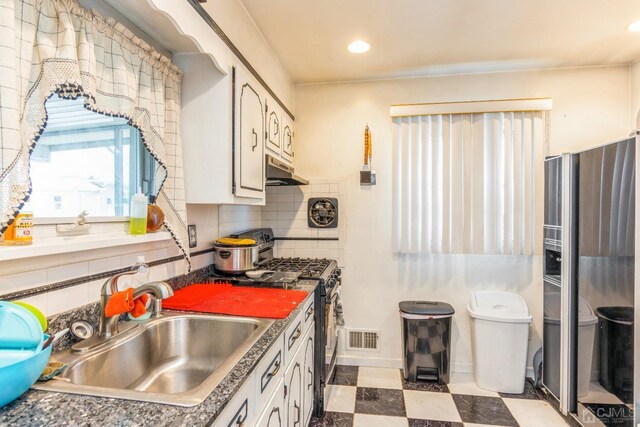 kitchen featuring stainless steel range with gas cooktop, sink, decorative backsplash, and white cabinets