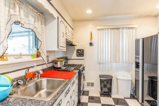 kitchen with visible vents, backsplash, black range with gas stovetop, a sink, and under cabinet range hood