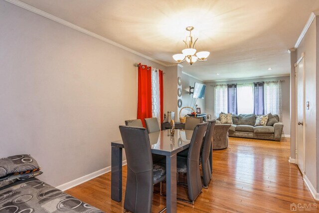 dining area featuring crown molding, a chandelier, and light hardwood / wood-style floors