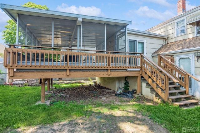 rear view of property featuring stairway, a sunroom, a yard, and a deck