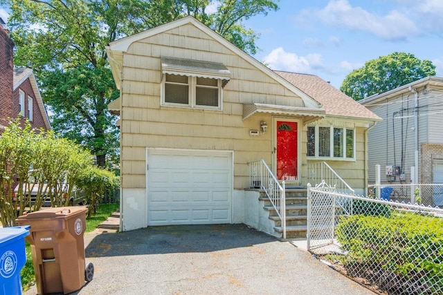 split level home featuring a garage, driveway, a shingled roof, and fence