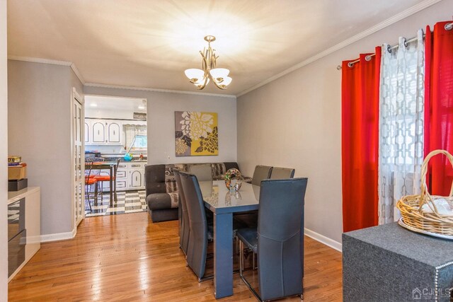 dining area with crown molding, a chandelier, and light hardwood / wood-style flooring