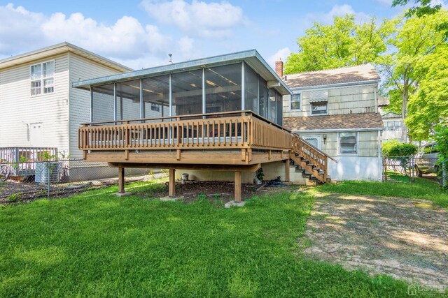 rear view of house with a lawn, a sunroom, and a deck