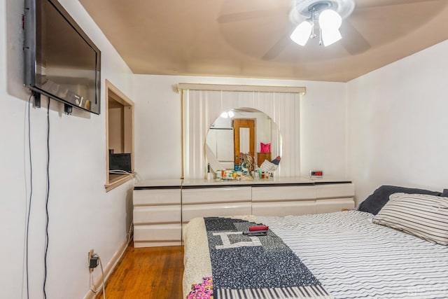 bedroom featuring a ceiling fan, baseboards, and wood finished floors