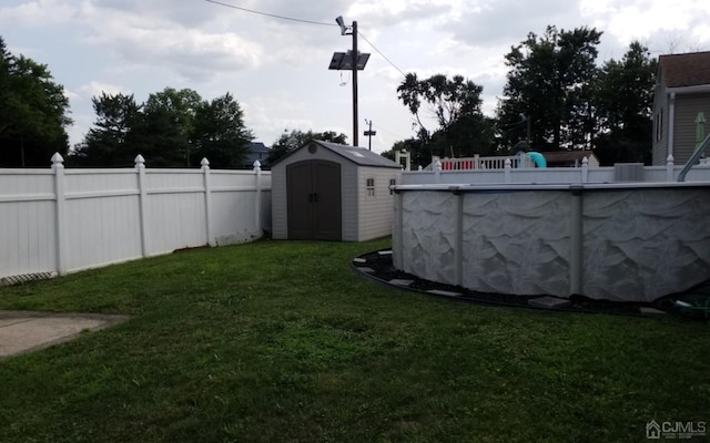 view of yard featuring a fenced in pool and a storage unit