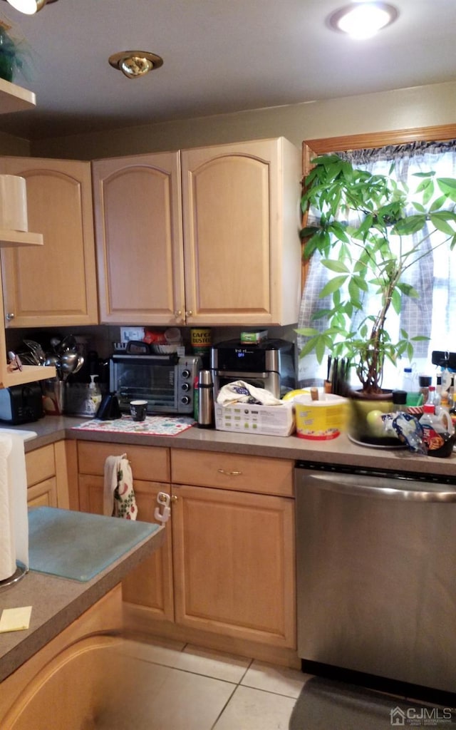 kitchen with stainless steel dishwasher, light brown cabinets, and light tile patterned floors