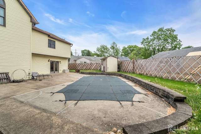 view of pool featuring a storage unit, a fenced backyard, a patio area, and an outdoor structure