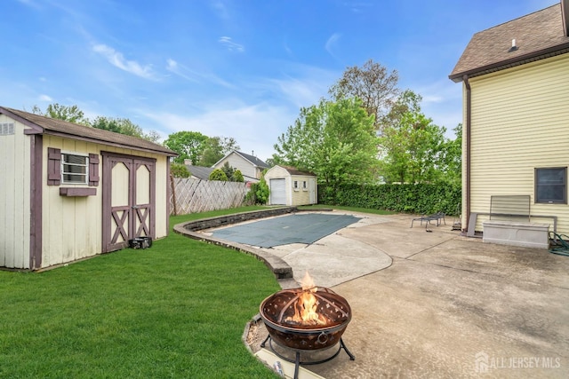 view of pool with a storage unit, an outdoor fire pit, an outdoor structure, and a patio