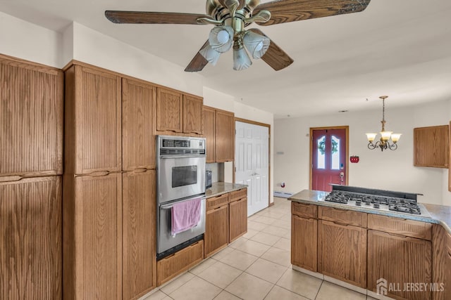 kitchen featuring appliances with stainless steel finishes, brown cabinetry, a ceiling fan, and light tile patterned flooring