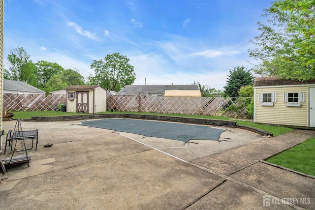 view of swimming pool with a storage unit, a fenced backyard, and an outdoor structure