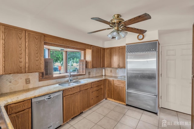 kitchen featuring stainless steel appliances, a sink, backsplash, and ceiling fan