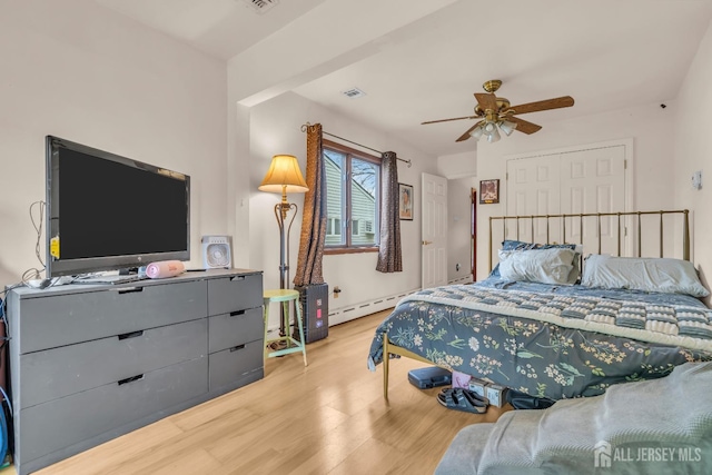 bedroom featuring light wood-type flooring, a baseboard heating unit, and ceiling fan