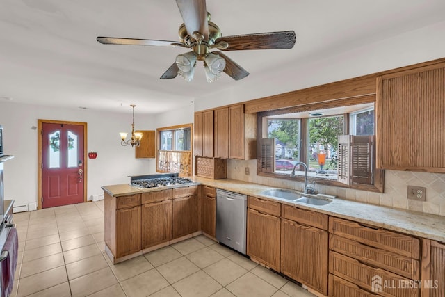 kitchen featuring stainless steel appliances, a sink, a peninsula, backsplash, and brown cabinets