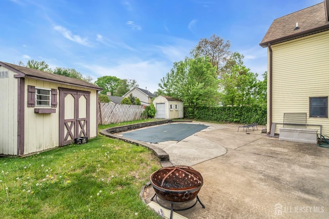 view of pool featuring a storage shed, a fire pit, an outbuilding, and a patio area