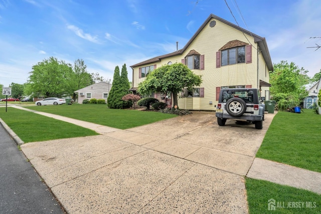 view of front of house featuring concrete driveway, a front lawn, and an attached garage