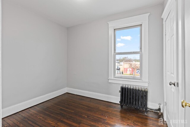 89 Woodbridge Ave, Highland Park, NJ 08904 - spare room featuring dark wood-style flooring, baseboards, and radiator heating unit