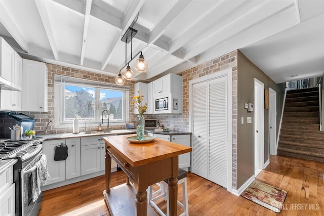11 Stockton Rd, New Brunswick, NJ 08901 - kitchen with appliances with stainless steel finishes, decorative backsplash, light wood-style flooring, beam ceiling, and white cabinetry