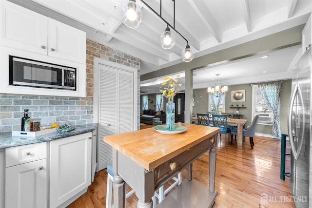 11 Stockton Rd, New Brunswick, NJ 08901 - kitchen featuring appliances with stainless steel finishes, white cabinetry, beamed ceiling, light wood-style floors, and hanging light fixtures