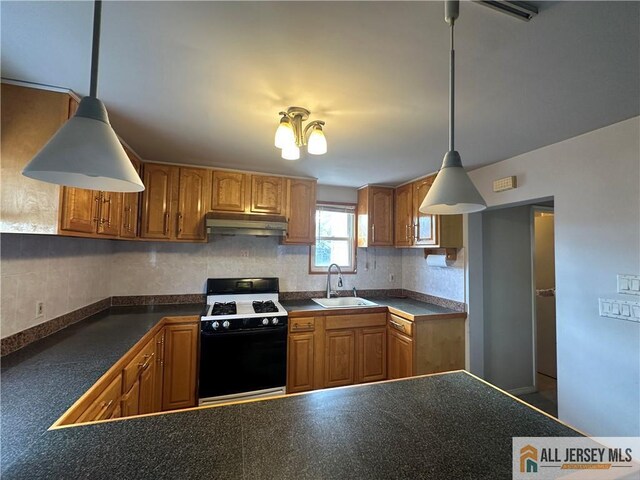 kitchen featuring range with gas cooktop, backsplash, pendant lighting, and sink