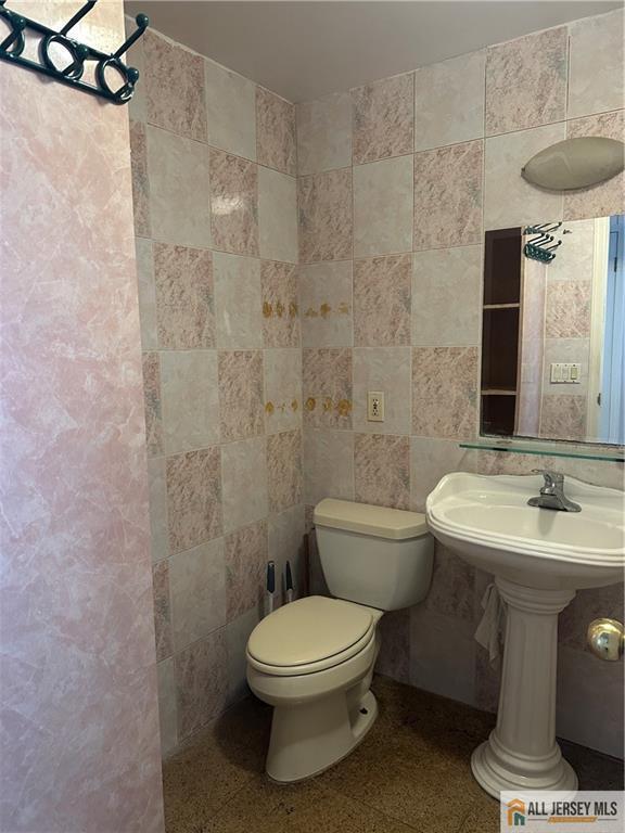 bathroom with tile walls and toilet