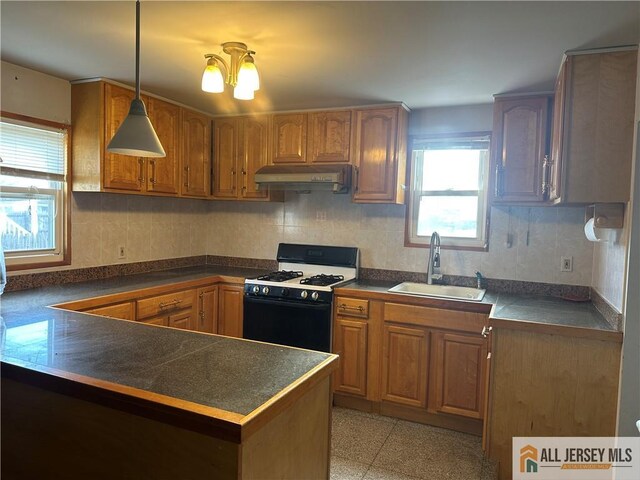 kitchen featuring range with gas stovetop, a chandelier, kitchen peninsula, sink, and decorative light fixtures