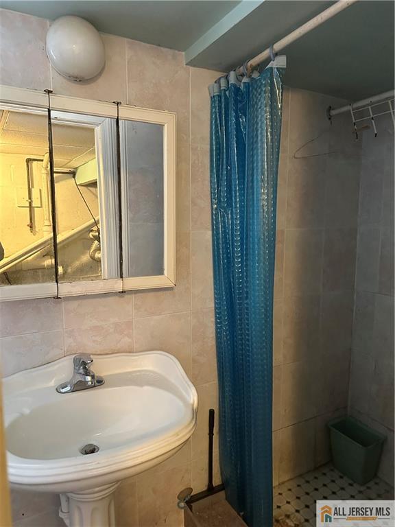 bathroom featuring sink, tile walls, backsplash, and a shower with curtain