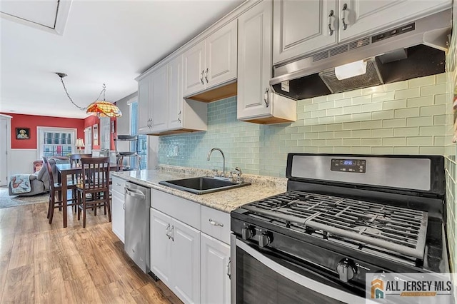 77 Navesink Ave, Middletown, NJ 07748 - kitchen featuring appliances with stainless steel finishes, under cabinet range hood, white cabinets, light wood-style floors, and backsplash