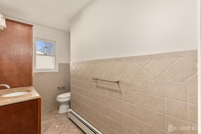 bathroom featuring vanity, a baseboard heating unit, tile walls, and toilet