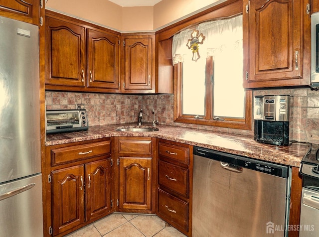 kitchen featuring backsplash, sink, light tile patterned floors, and appliances with stainless steel finishes