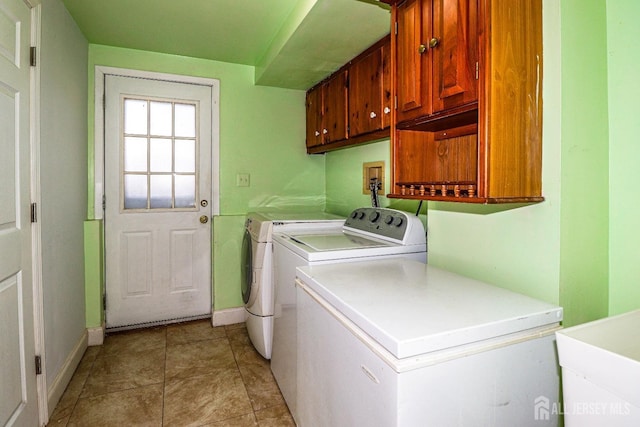 washroom featuring washing machine and dryer, sink, light tile patterned floors, and cabinets