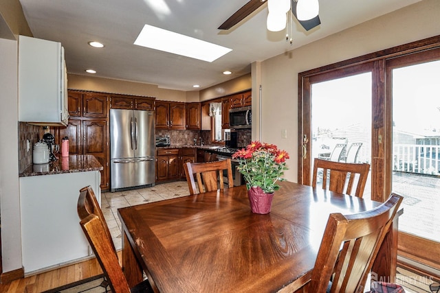 dining area with a skylight, light hardwood / wood-style flooring, and ceiling fan