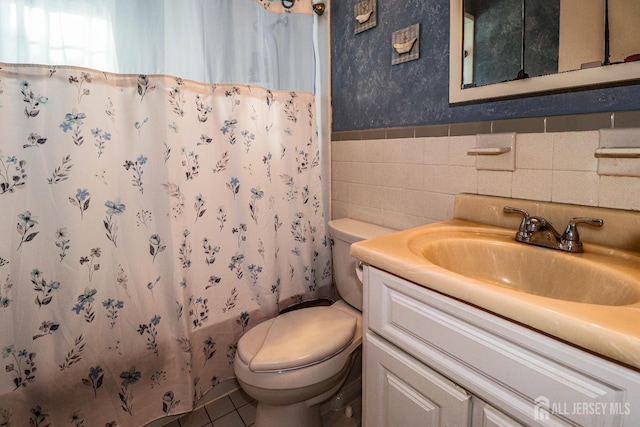 bathroom with tile patterned floors, vanity, tile walls, and toilet