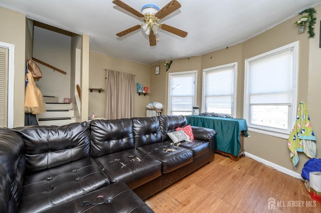 living room with a ceiling fan, stairway, baseboards, and wood finished floors