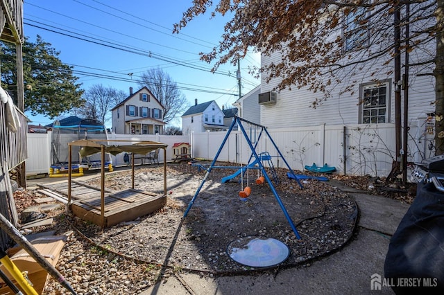 view of yard with a fenced backyard, a playground, and a wall mounted AC