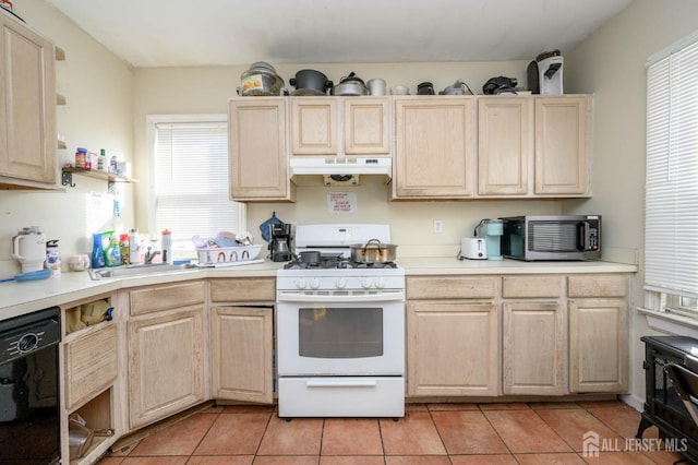 kitchen with black dishwasher, white gas range oven, under cabinet range hood, light brown cabinets, and a sink