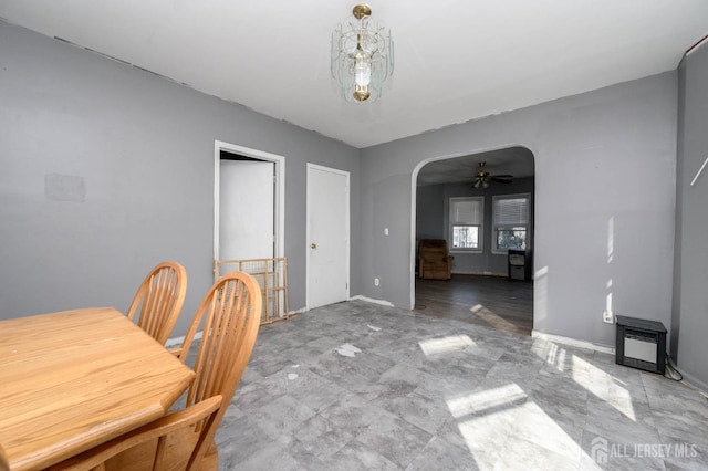 dining area with arched walkways, ceiling fan, and baseboards