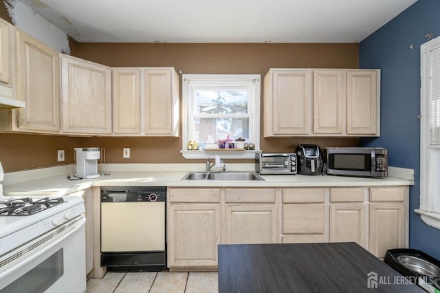 kitchen featuring light tile patterned floors, light countertops, light brown cabinetry, a sink, and white appliances