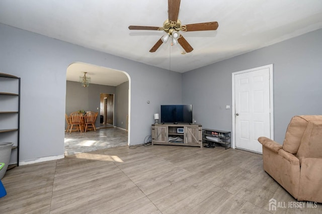 living area featuring arched walkways and a ceiling fan