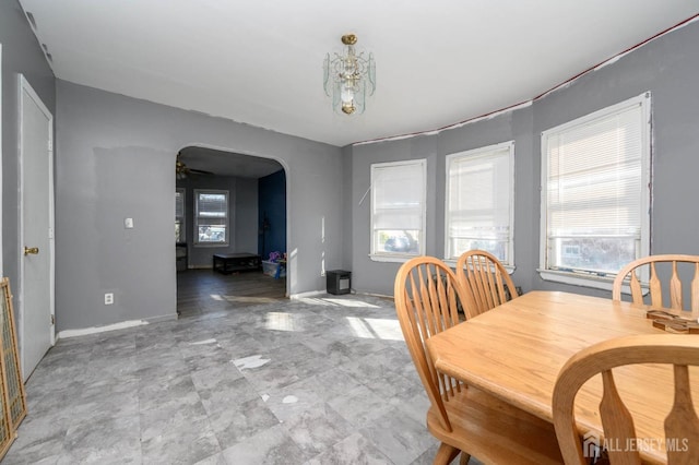 dining room with arched walkways, ceiling fan, and baseboards