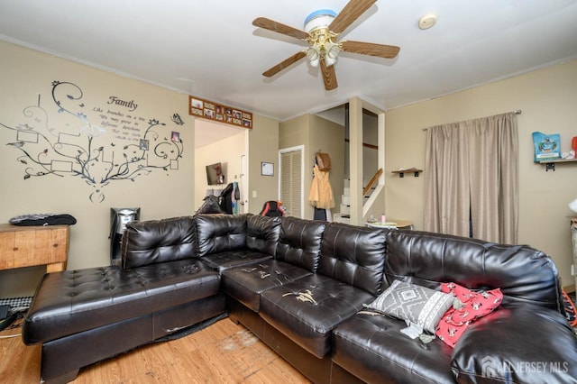 living area featuring ceiling fan, stairway, and wood finished floors