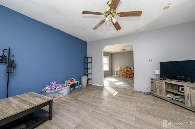 recreation room featuring arched walkways and a ceiling fan