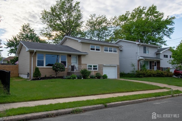 tri-level home featuring an attached garage, a front yard, driveway, and brick siding
