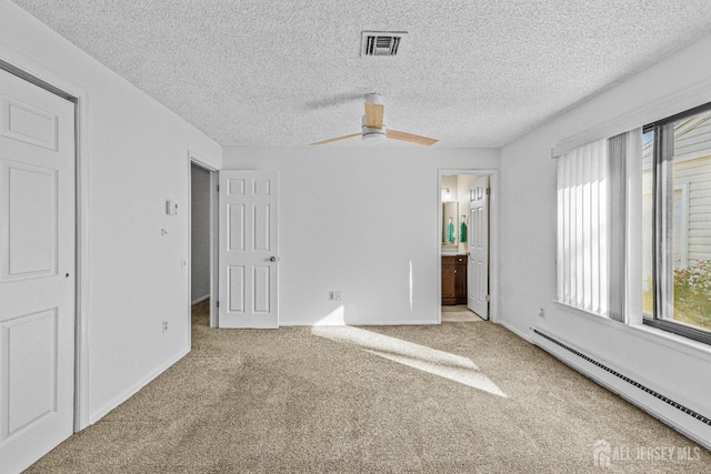 unfurnished bedroom featuring carpet, ensuite bathroom, ceiling fan, a baseboard heating unit, and multiple windows