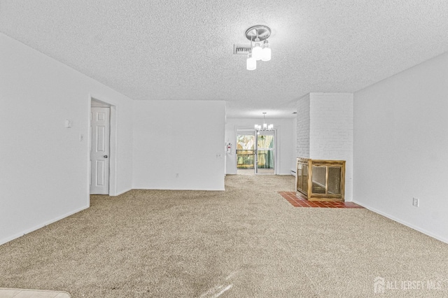 unfurnished living room with carpet flooring, a textured ceiling, a notable chandelier, and a brick fireplace